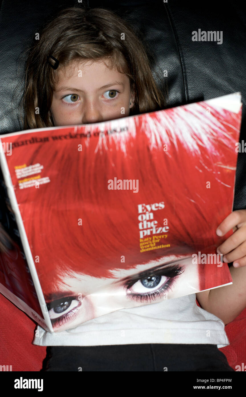 Young girl reading a story about the the American pop star Katy Perry in the Guardian weekend magazine Stock Photo