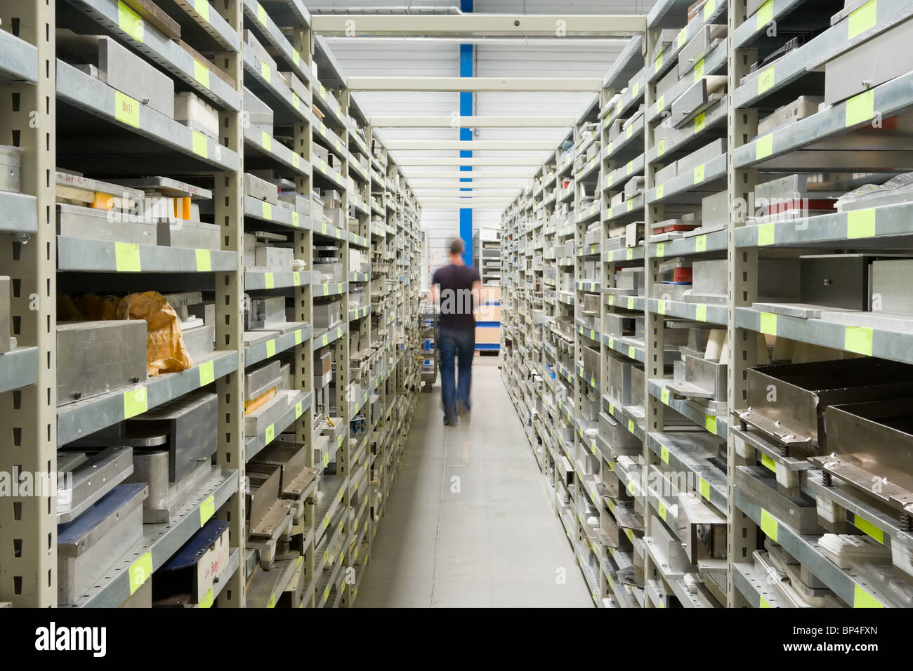 Metal Shelves With Spare Parts And Technician In Plant interior Stock Photo