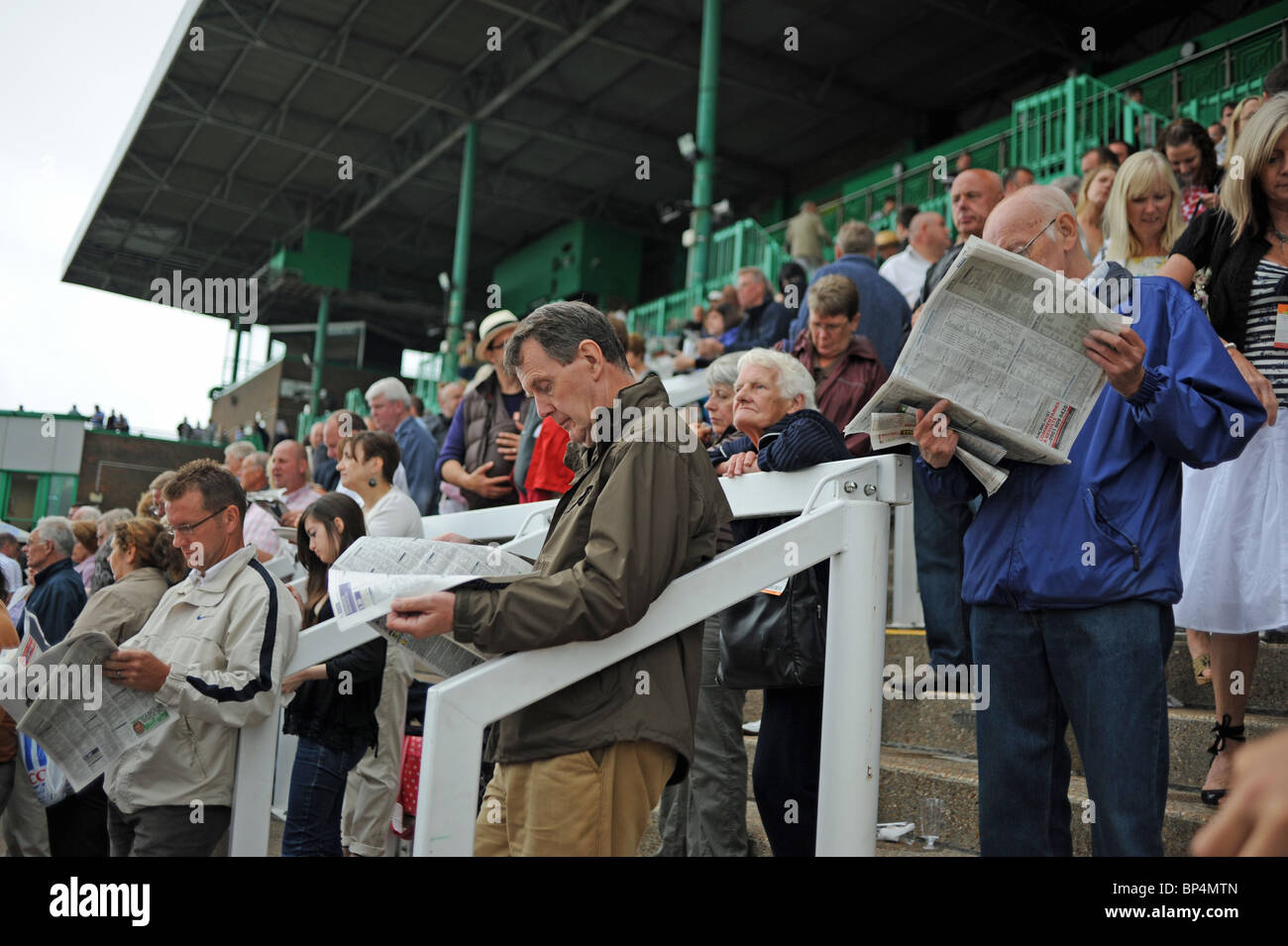 Crowds of punters at Brighton Races UK reading racing papers Stock Photo