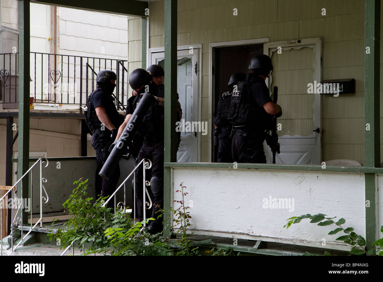 Police Tactical team from Street Narcotics Unit approach residence to serve a drug related high risk search warrant. KC/MO PD. Stock Photo