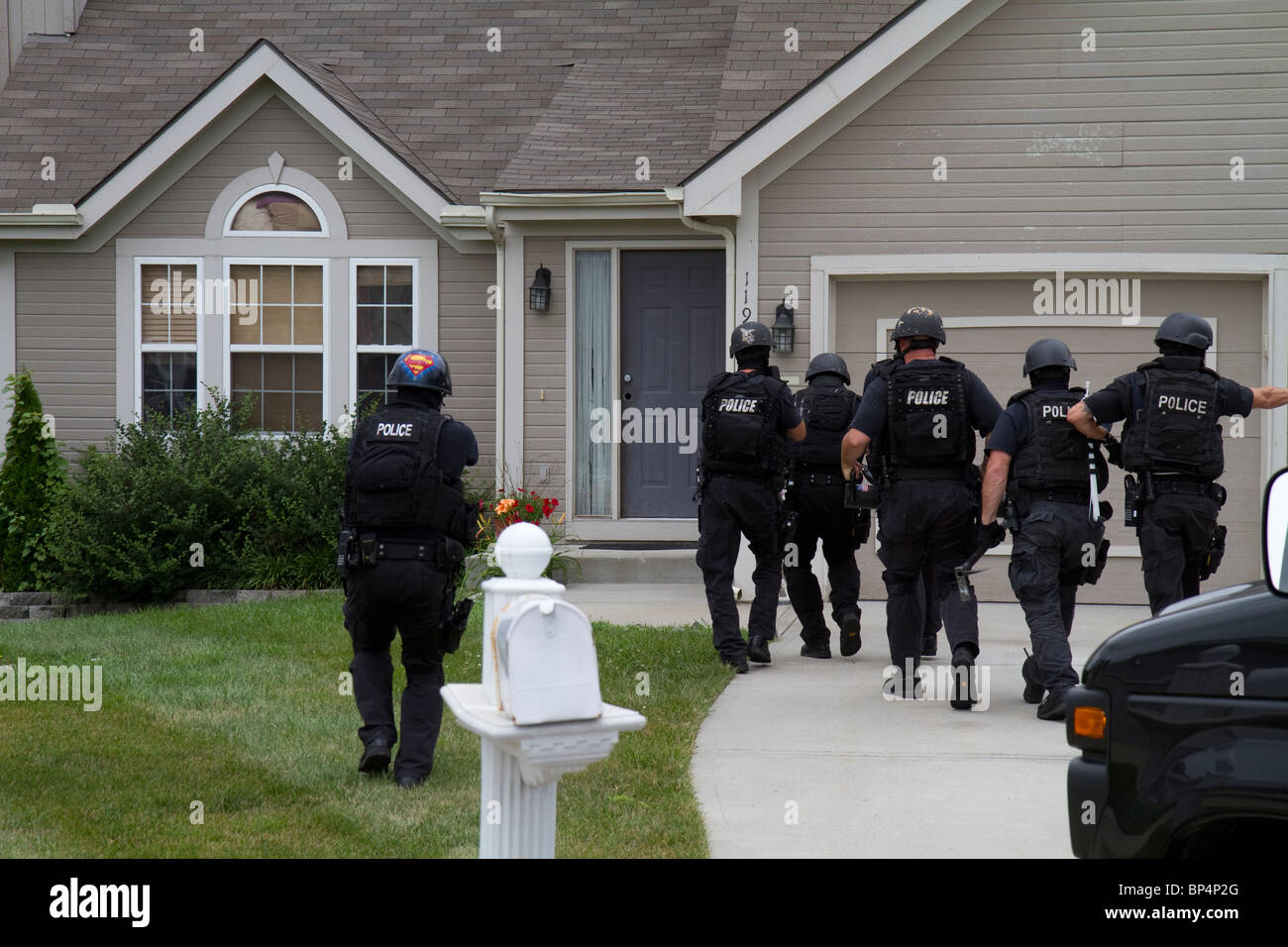 Police Tactical team from Street Narcotics Unit approach residence to serve a drug related high risk search warrant. KC/MO PD. Stock Photo