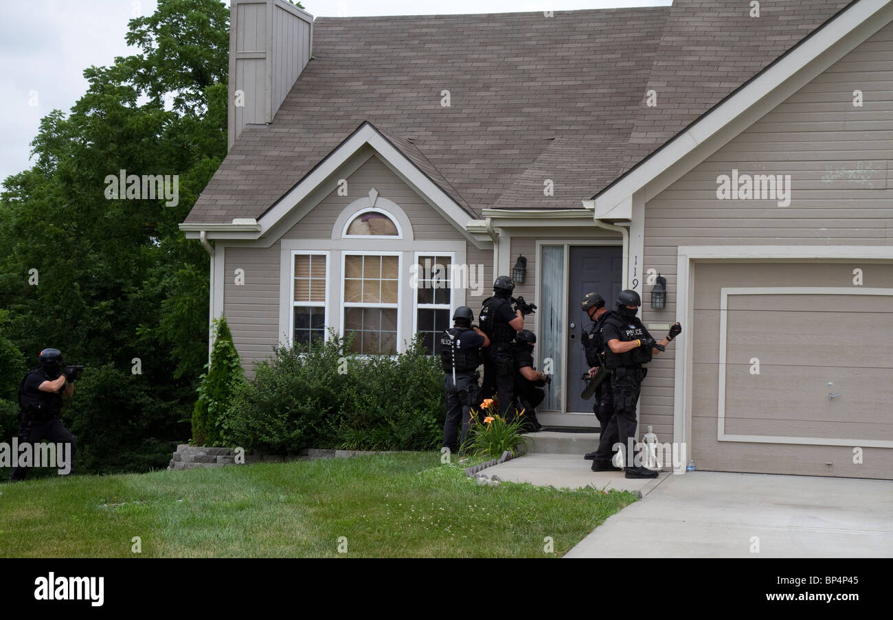 Police Tactical team from Street Narcotics Unit approach residence to serve a drug related high risk search warrant. KC/MO PD. Stock Photo
