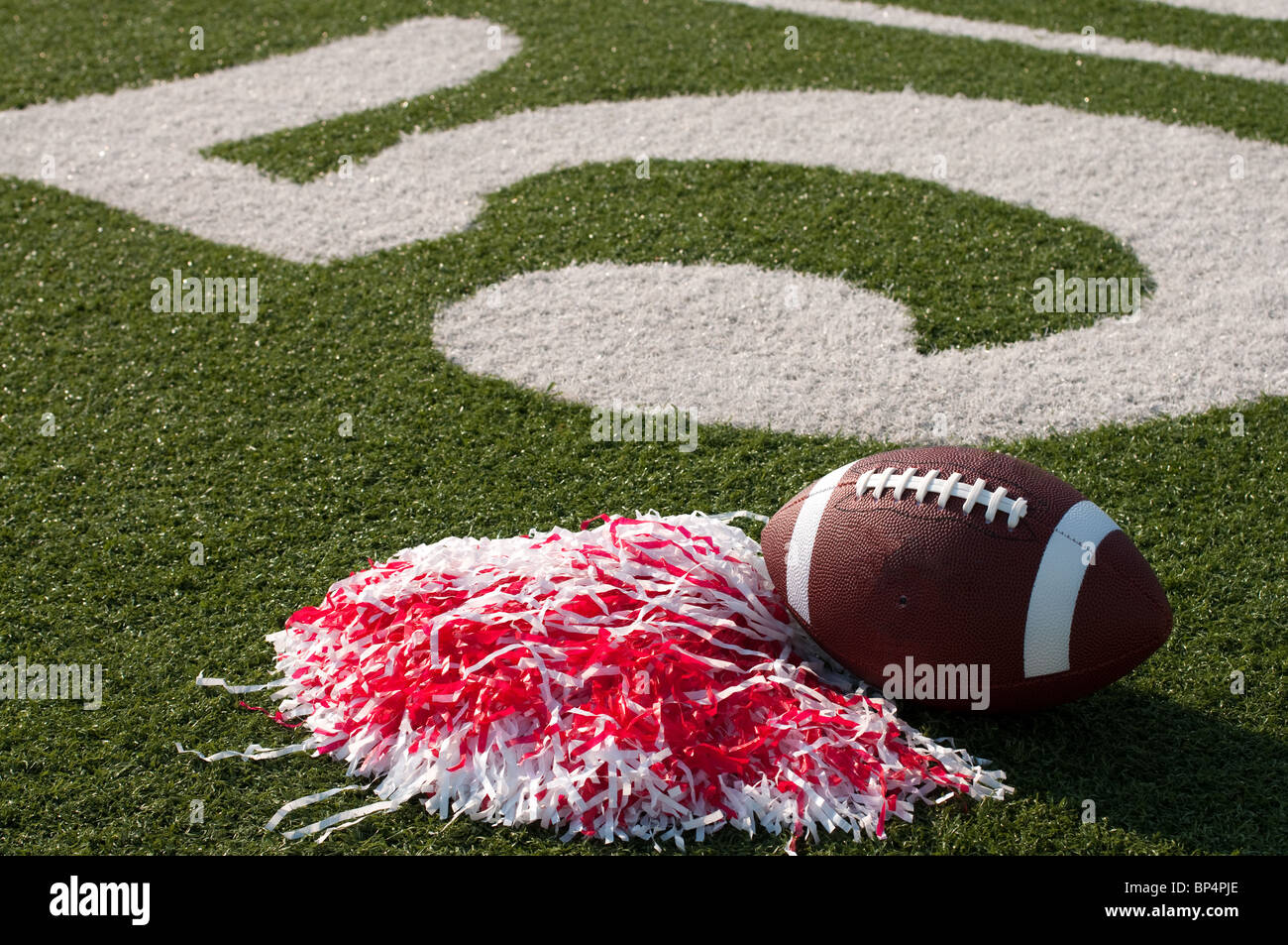 American football and pom poms on field. Stock Photo