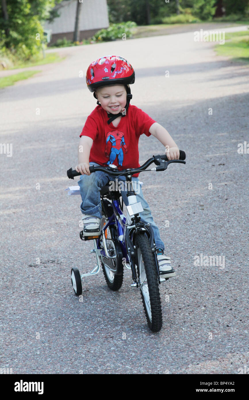 Little boy toddler riding his first bicycle with stabilisers MODEL RELEASED Stock Photo