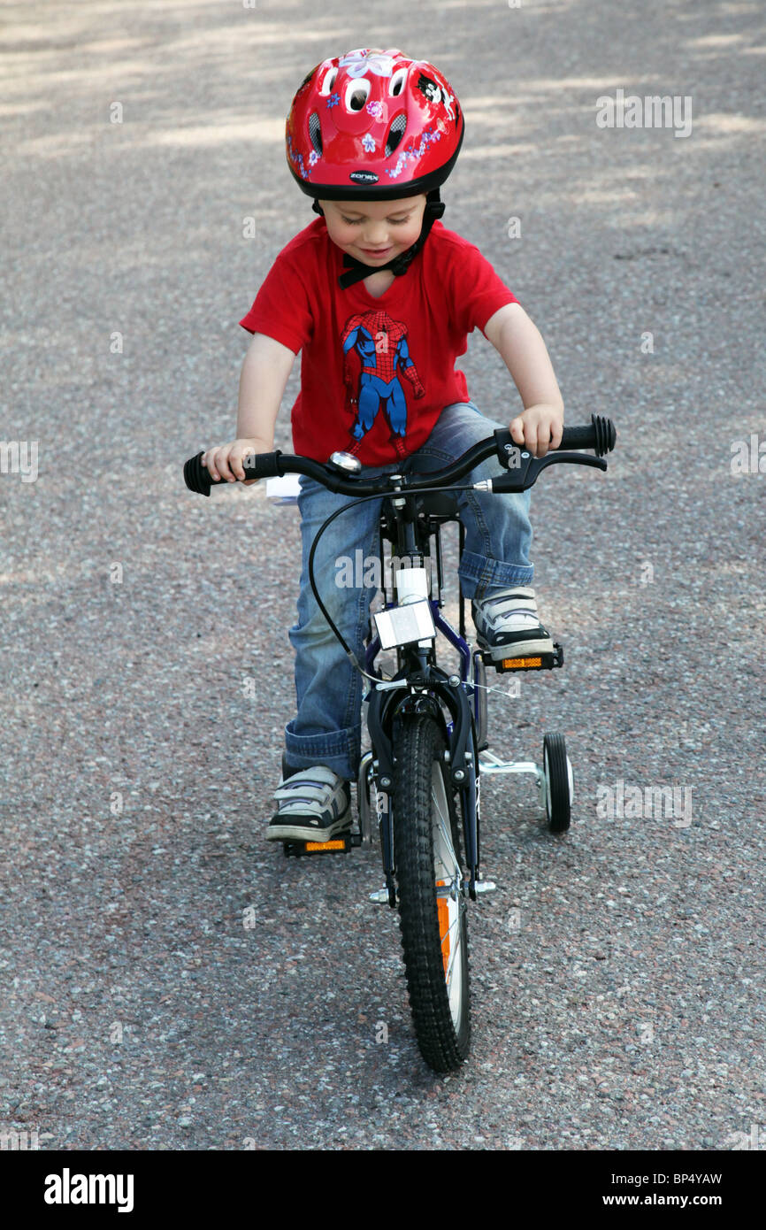 Little boy toddler riding his first bicycle with stabilisers MODEL RELEASED Stock Photo