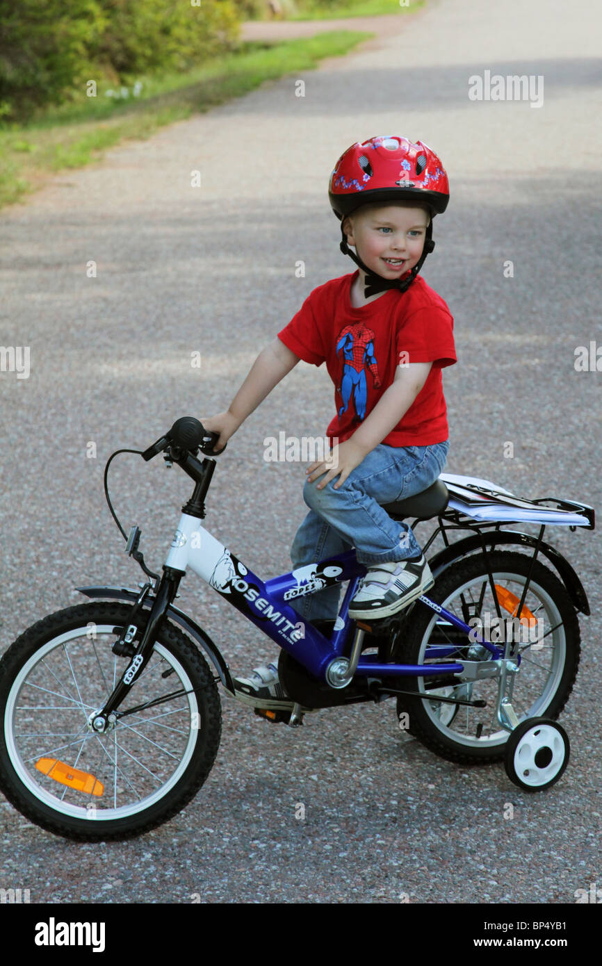 Little boy toddler riding his first bicycle with stabilisers MODEL RELEASED Stock Photo