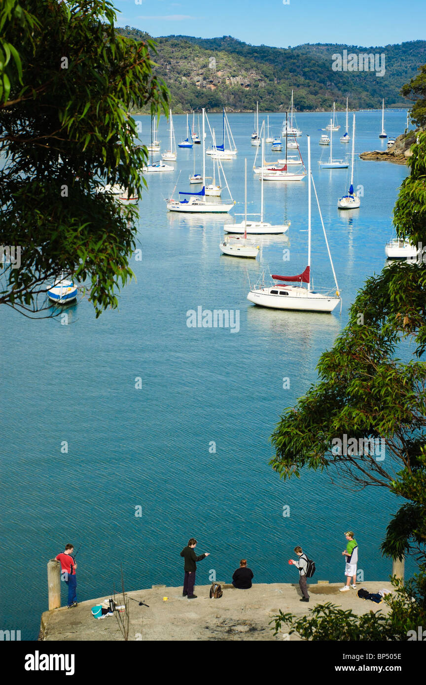A family fishes in front of yachts moored on a quiet river. Click for details. Stock Photo