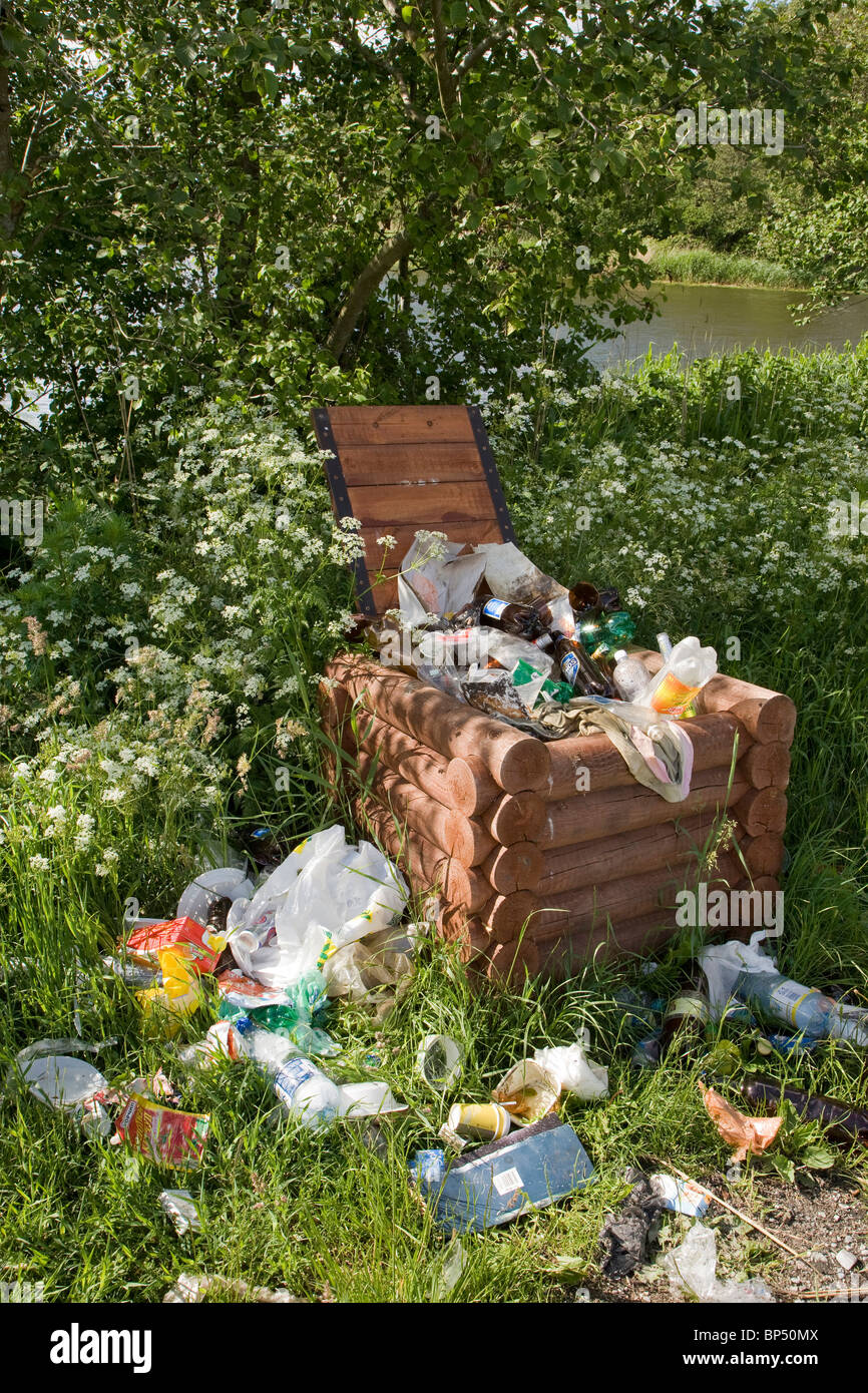 Litter spilling over from waste bin in car park in rural setting. Stock Photo