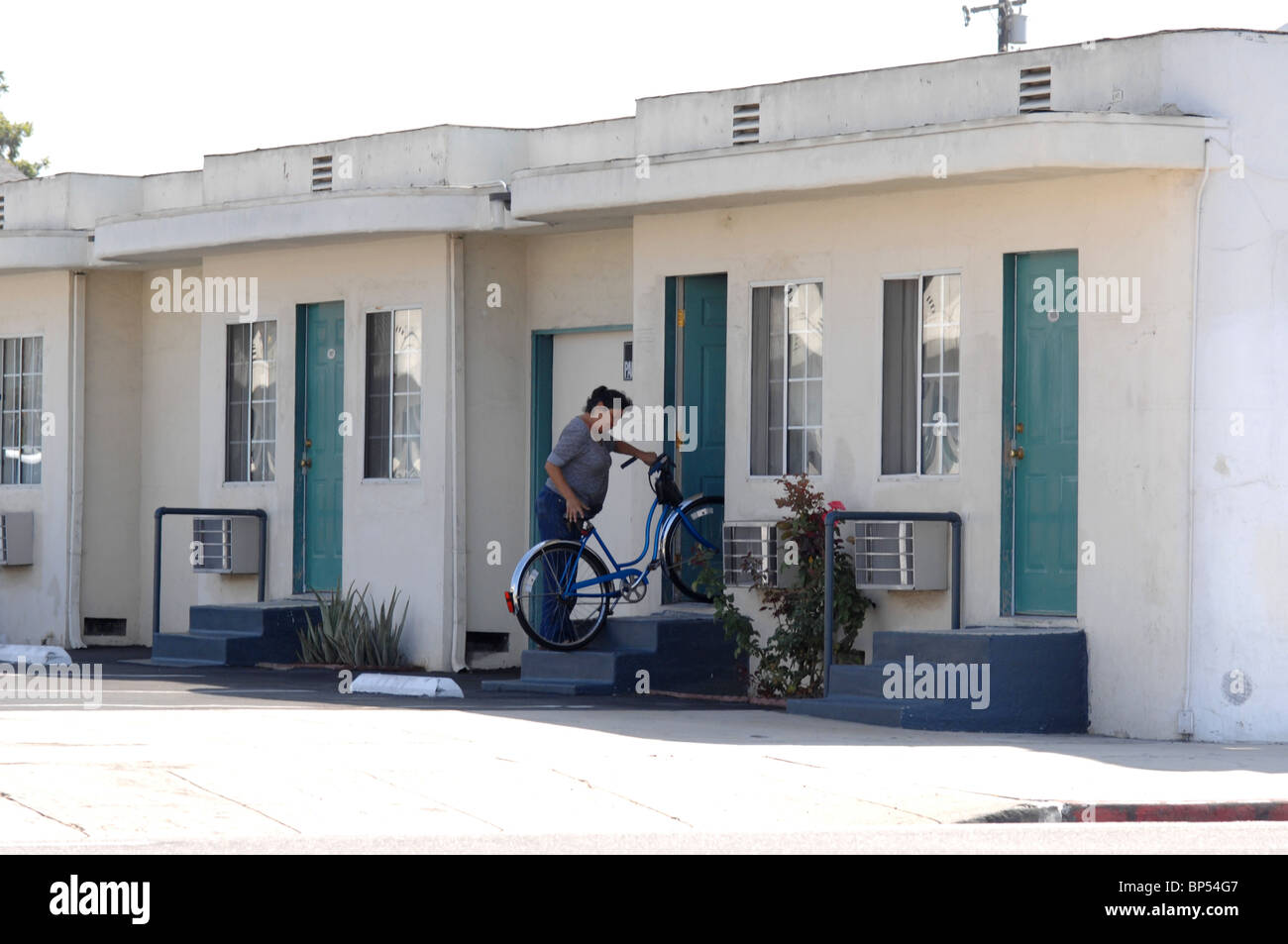 A woman bringing a bicycle into her dwelling. Stock Photo