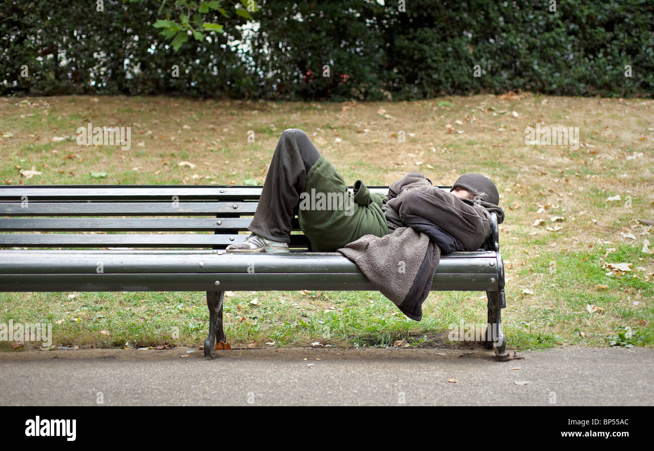 A homeless man sleeping on a bench in central London,England Stock Photo