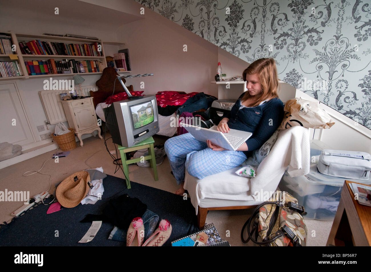 Teenaged girl watching television and working on laptop computer Stock Photo