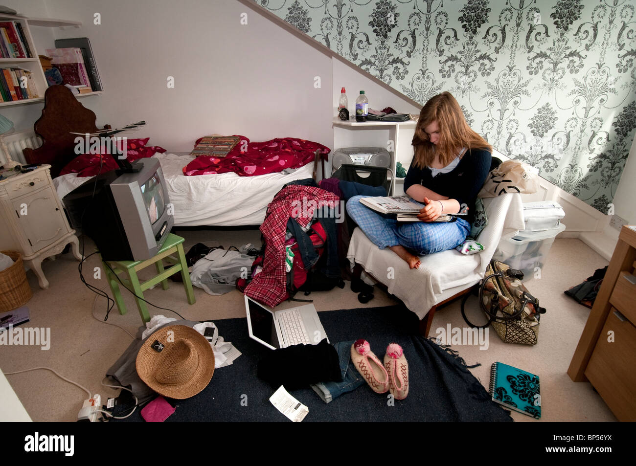 Teenaged girl in bedroom working on homework with Televisions on Stock Photo