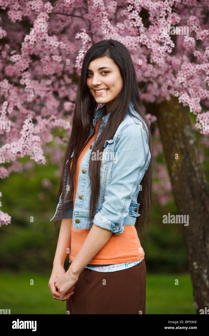 Portland, Oregon, United States Of America; A Teenage Girl By A Tree Full Of Blossoms In Portland Park Stock Photo