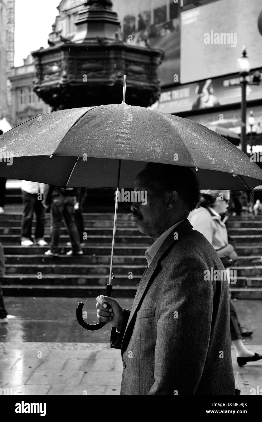 North African Man with umbrella in Piccadilly Circus Stock Photo