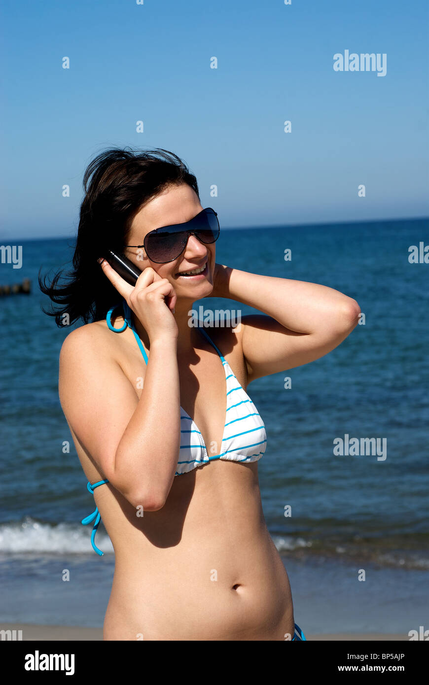 A young woman speaking on the phone on the beach Stock Photo