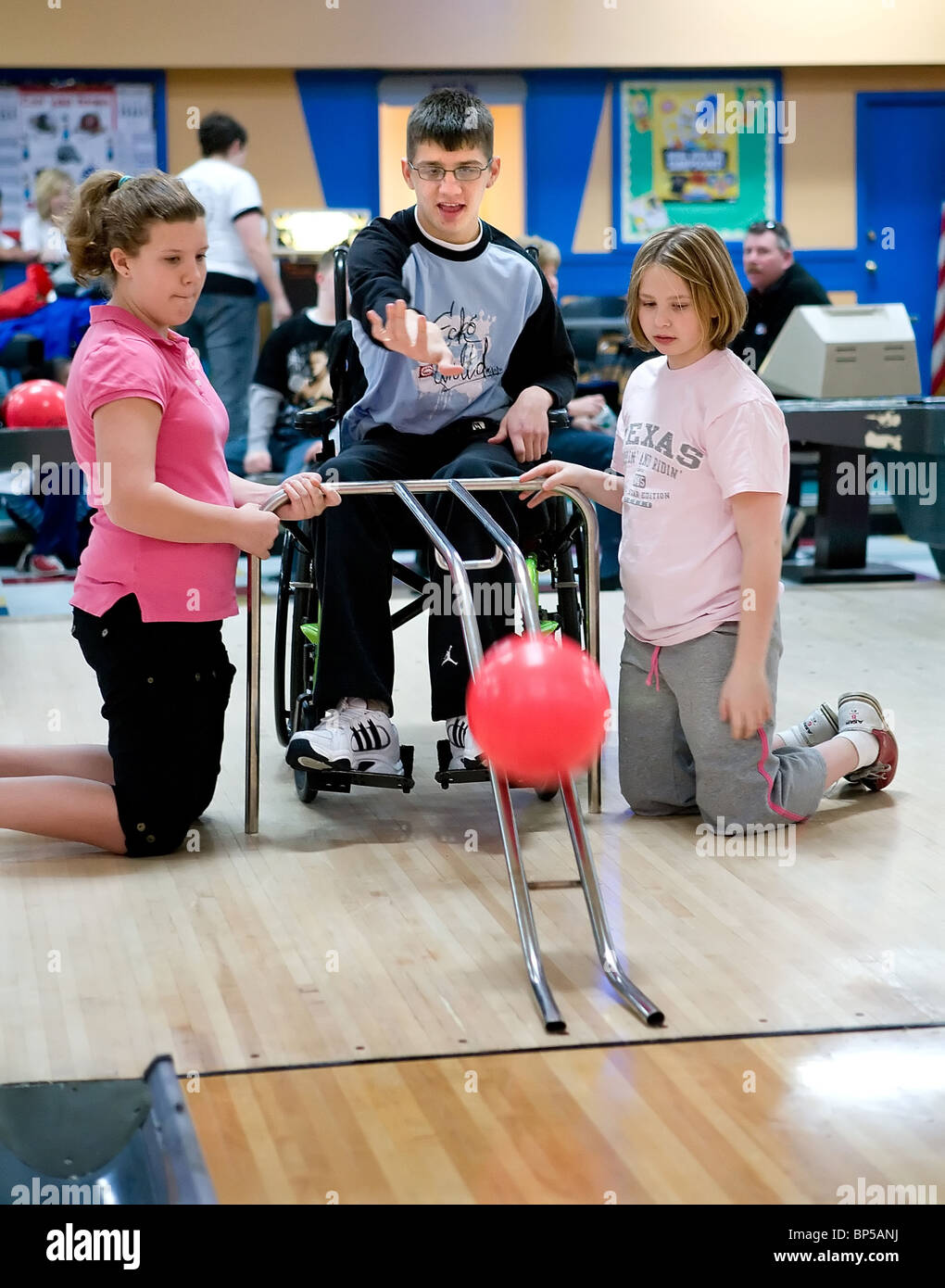 A child with a physical disability uses a guide to bowl at a CT USA Bowling alley on a field trip with his class Stock Photo