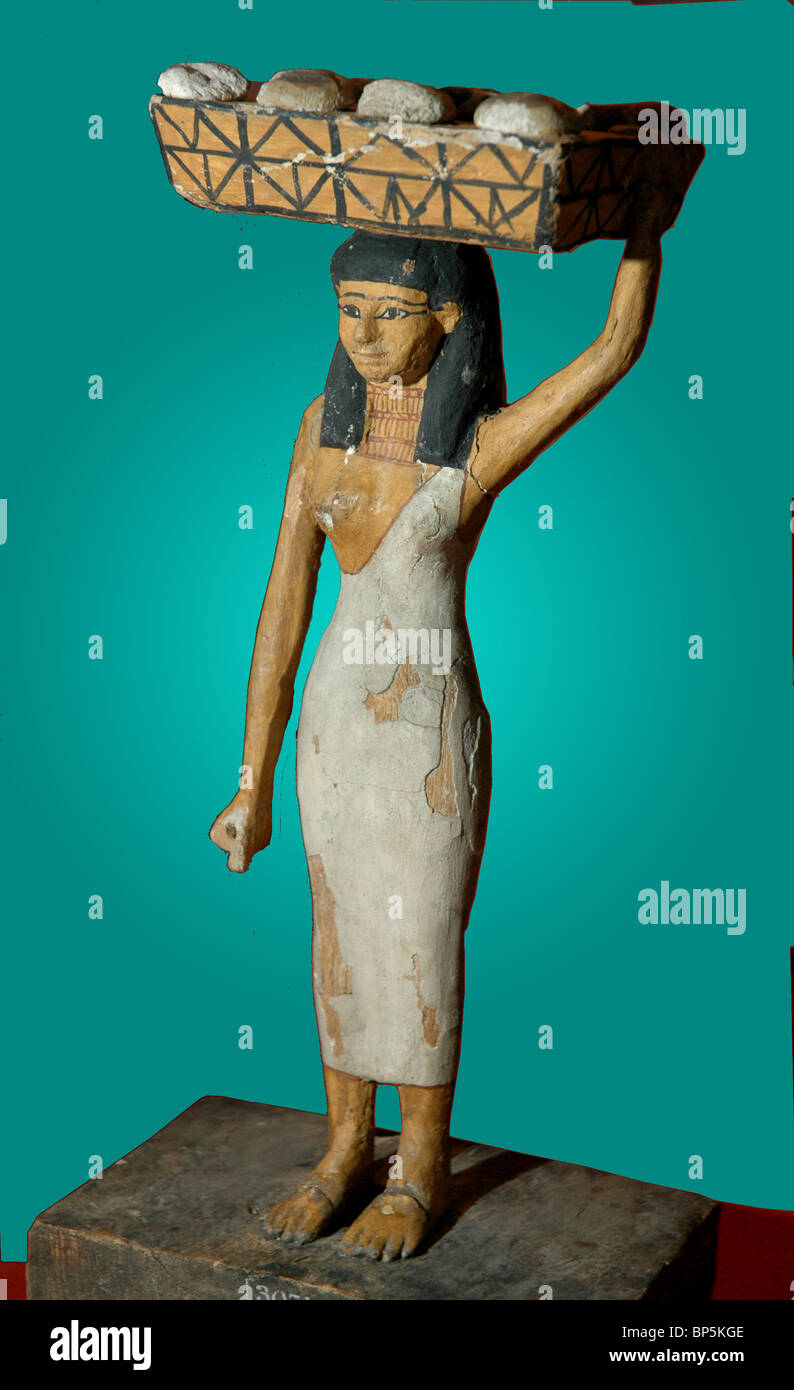 5225. EGYPTIAN FEMALE SERVANT GIRL CARRYING A BASKET WITH OFFERINGS, LOAVES OF BREAD AND OTHER. NATIVE WOOD, C. 1950 BC Stock Photo