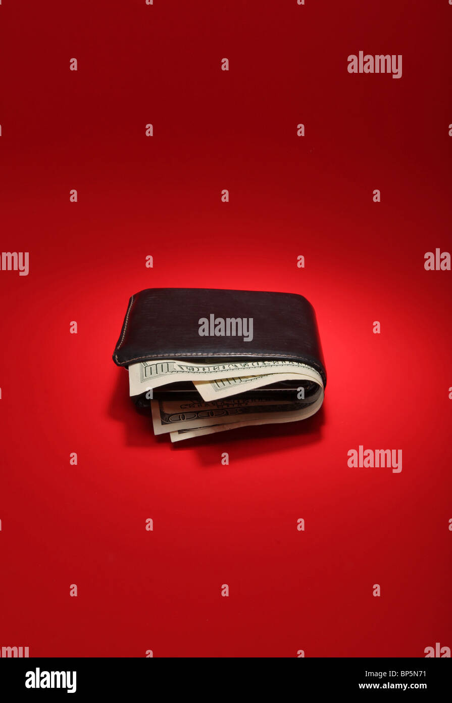 A black leather wallet with money on a bright red background, currency is 300 dollars Stock Photo