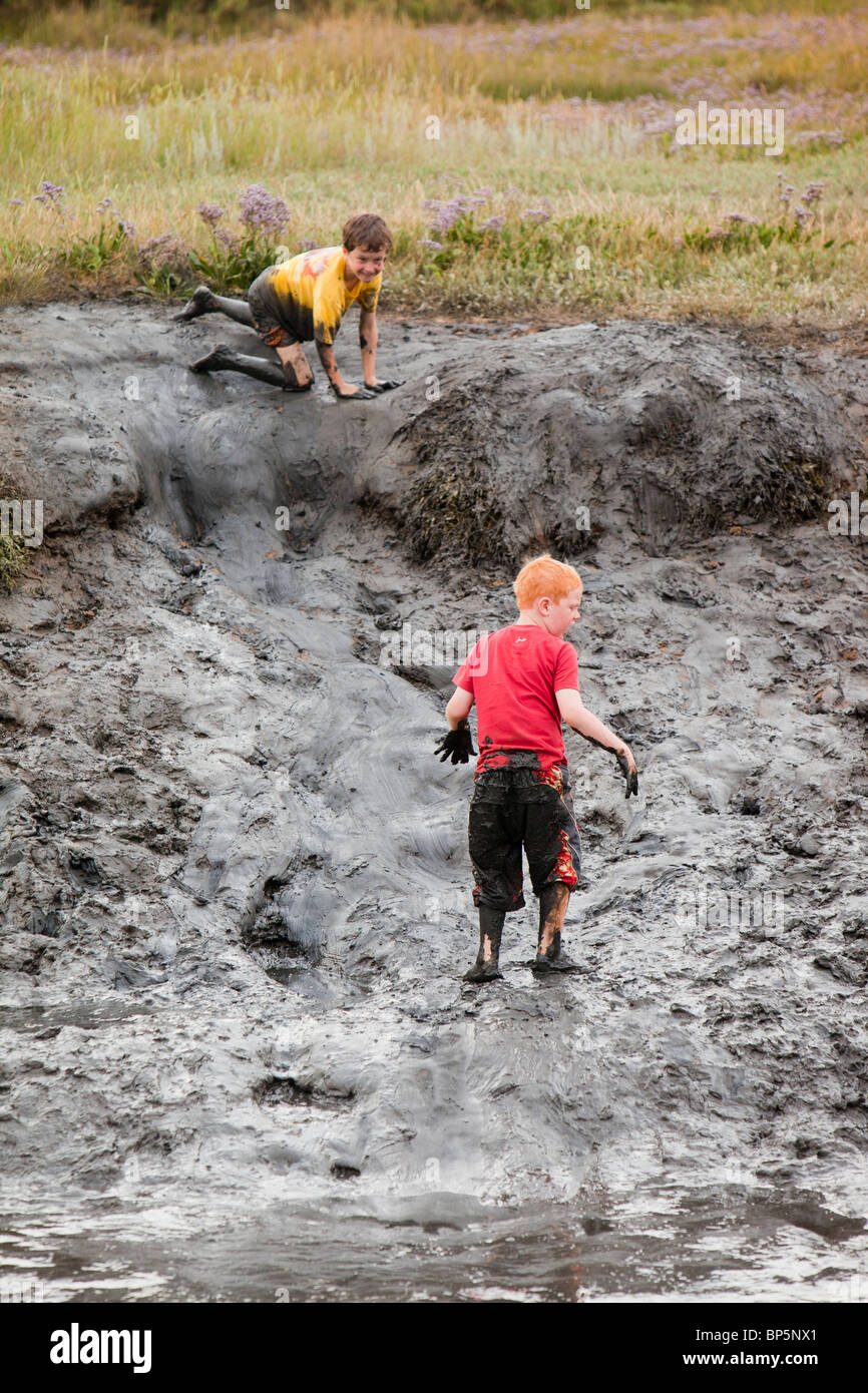 Children playing in a muddy creek at Blakeney, North Norfolk, UK. Stock Photo