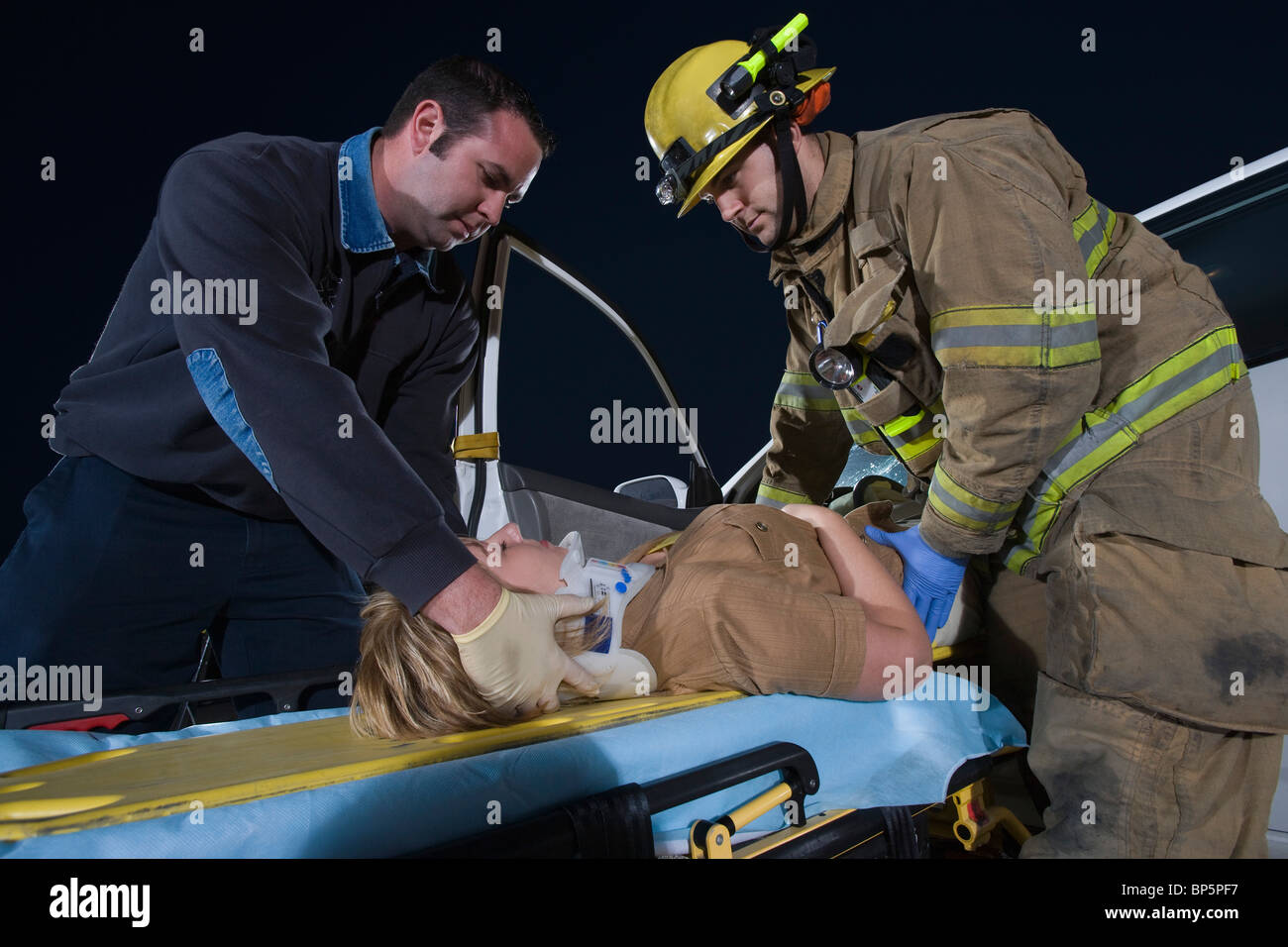 Firefighter and paramedic rescuing car accident victim Stock Photo Alamy