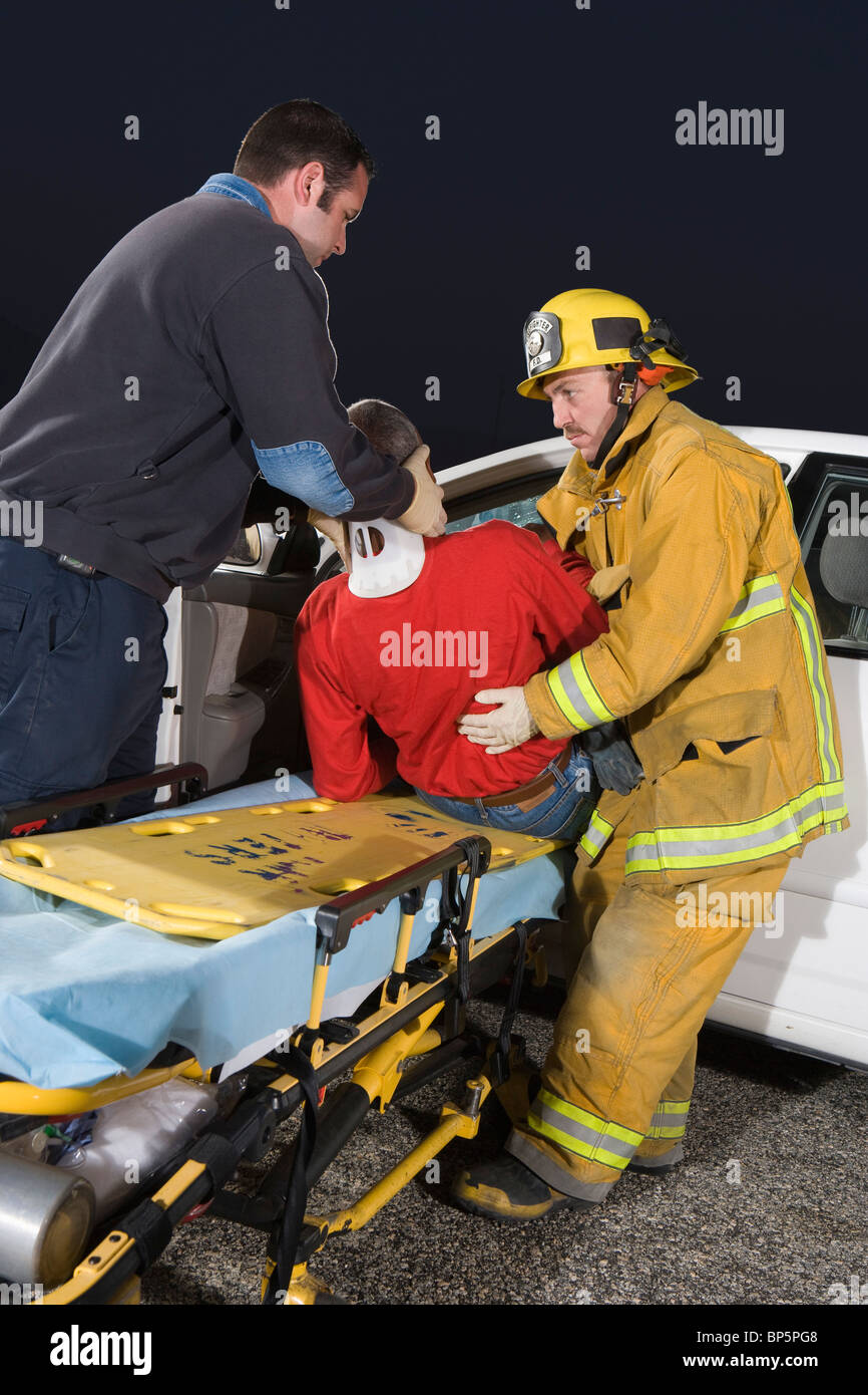 Firefighter and paramedic rescuing car accident victim Stock Photo