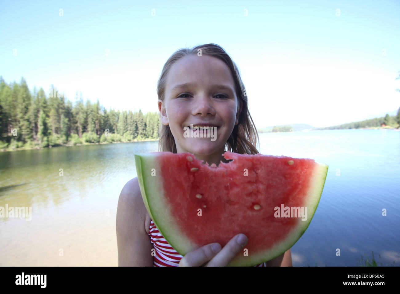 girl 8-10 years old eating watermelon by lake Stock Photo