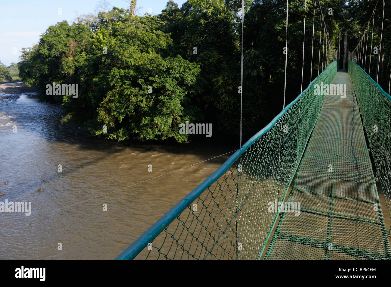 A suspension bridge leading to primary tropical rainforest, Chilamate, Costa Rica. The bridge is over the Sarapiqui River Stock Photo