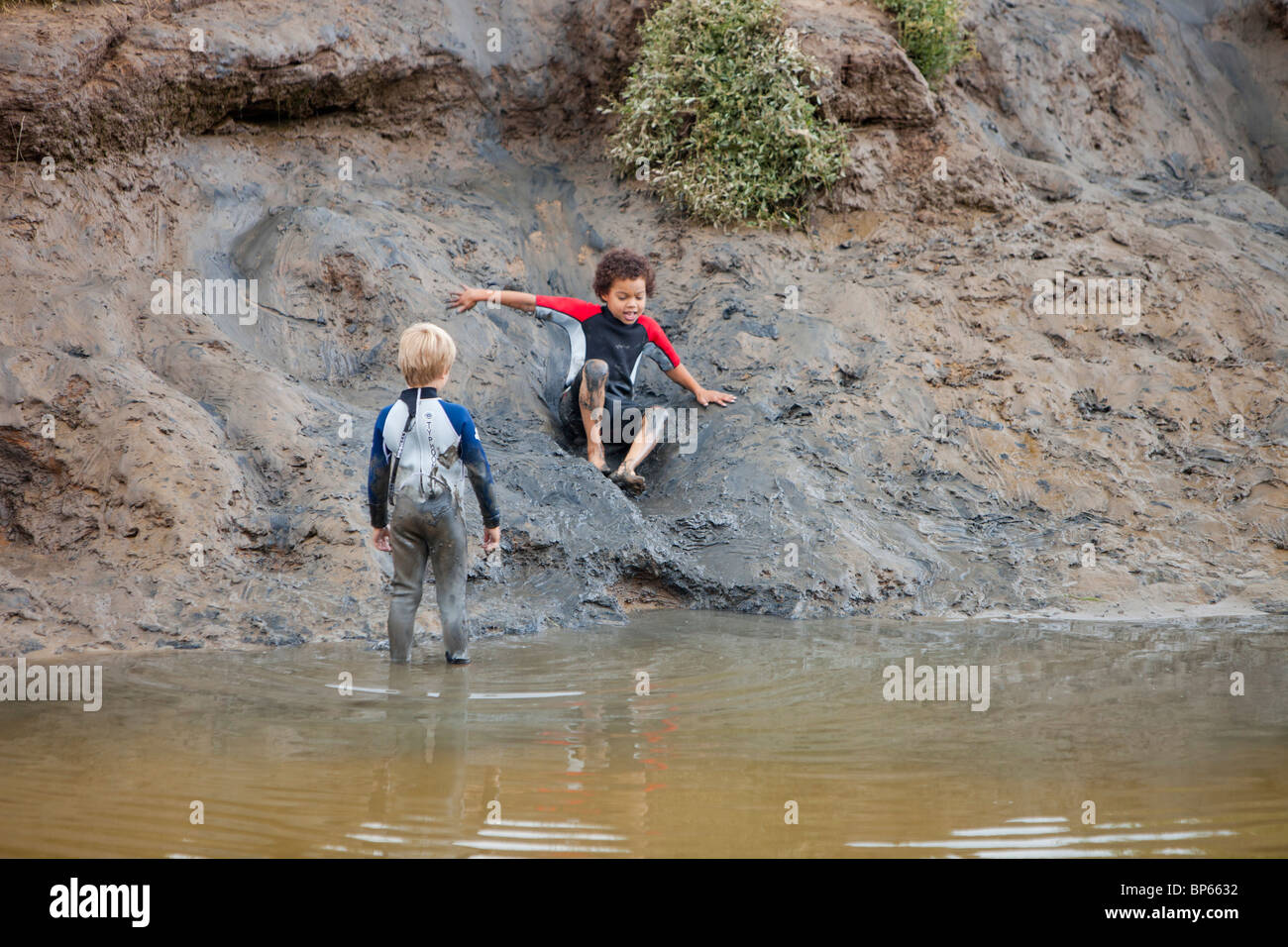 Boys playing in a muddy creek in Blakeney, Norfolk, UK. Stock Photo