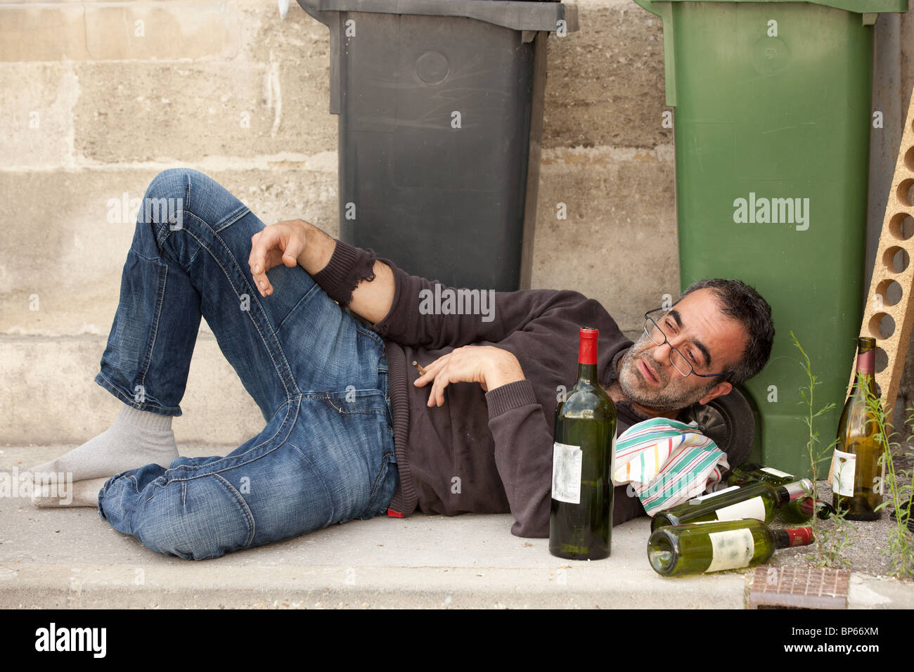 drunk man lying near trashcan in city street Stock Photo