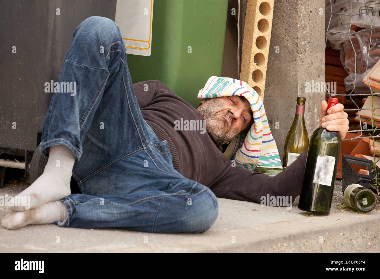 drunk man lying near trashcan in city street Stock Photo