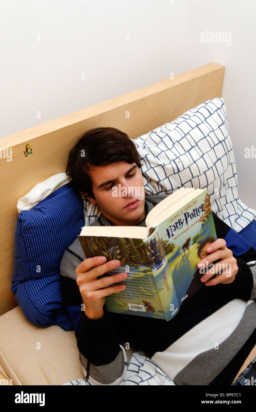 Teenager reading Harry Potter in german laying on his bed Stock Photo