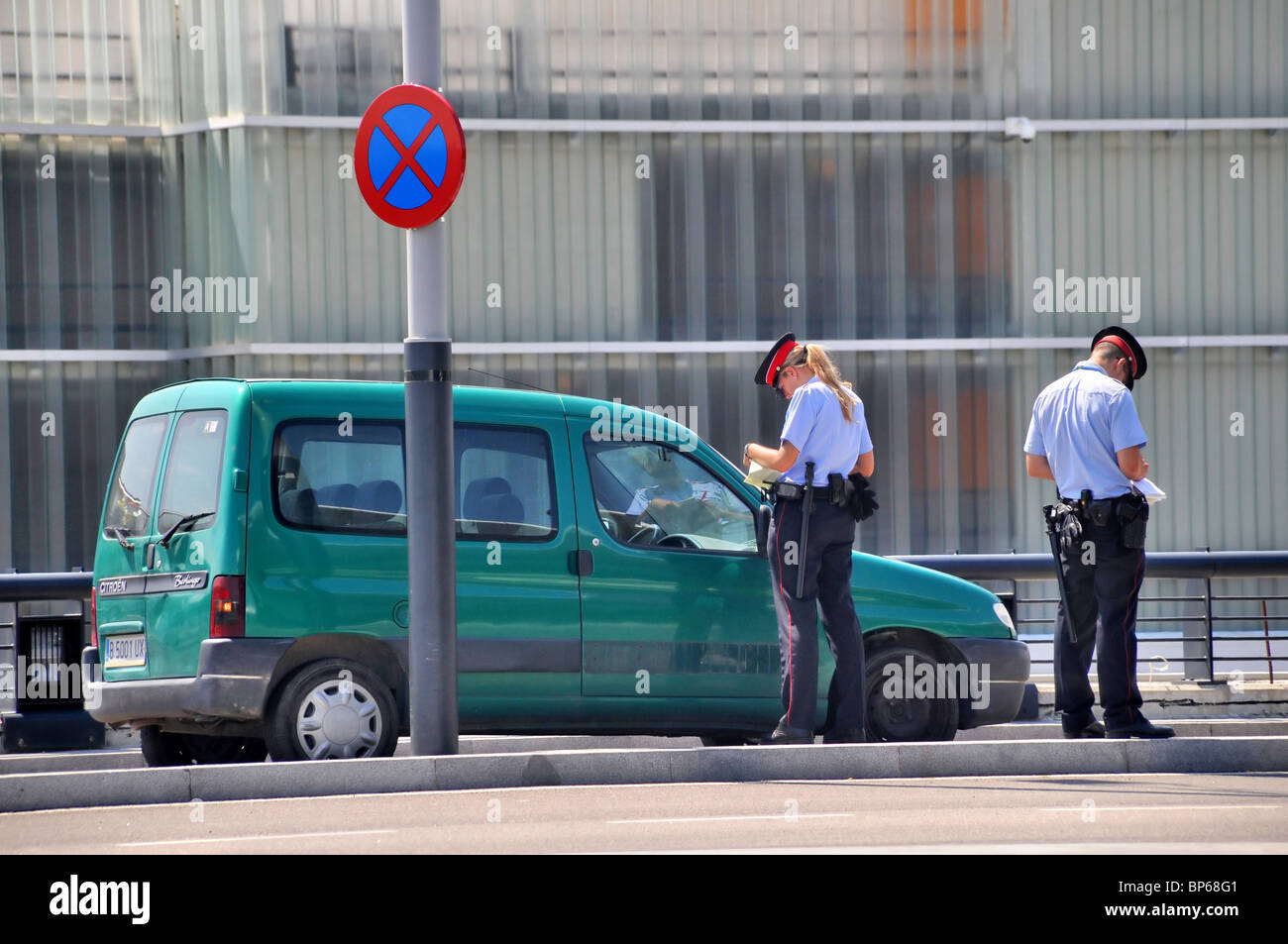 Two Spanish traffic cops / wardens  take down details of an illegally parked car. Stock Photo