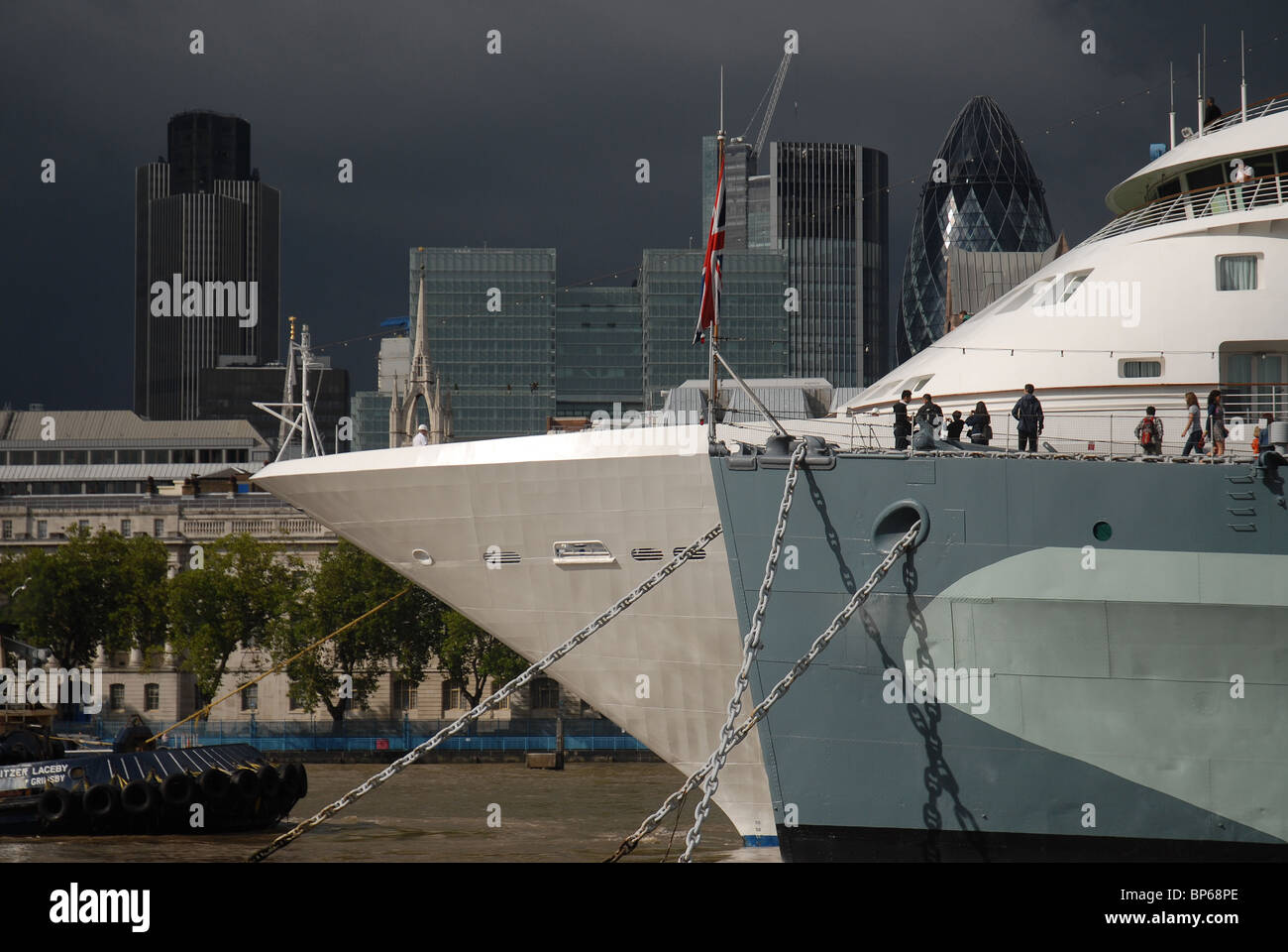Cruise liner Silver Cloud moored next to HMS Belfast on the River Thames with The Natwest Tower and Gherkin in the background Stock Photo