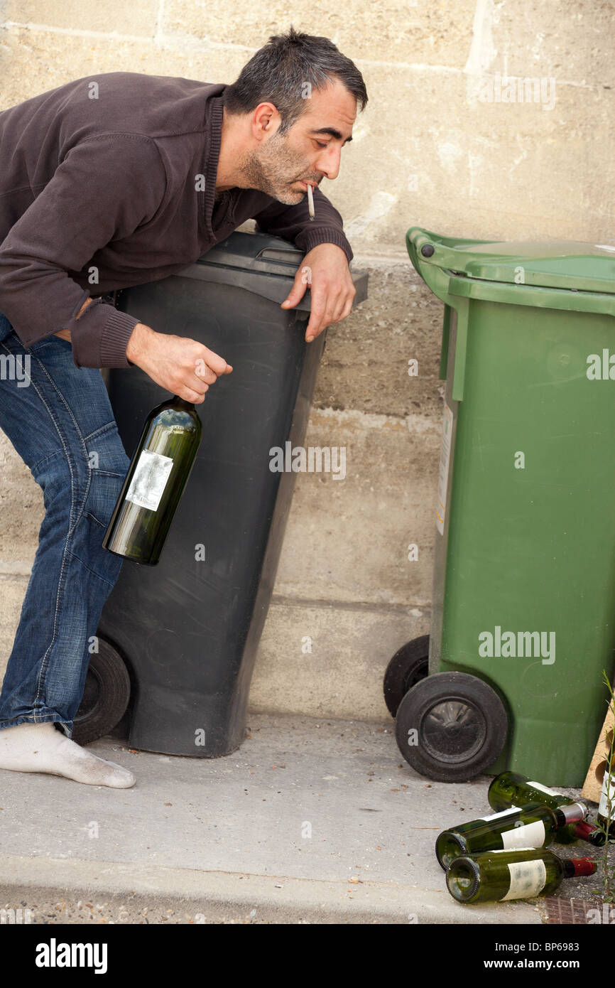 poor homeless man standing near trashcan in city street Stock Photo