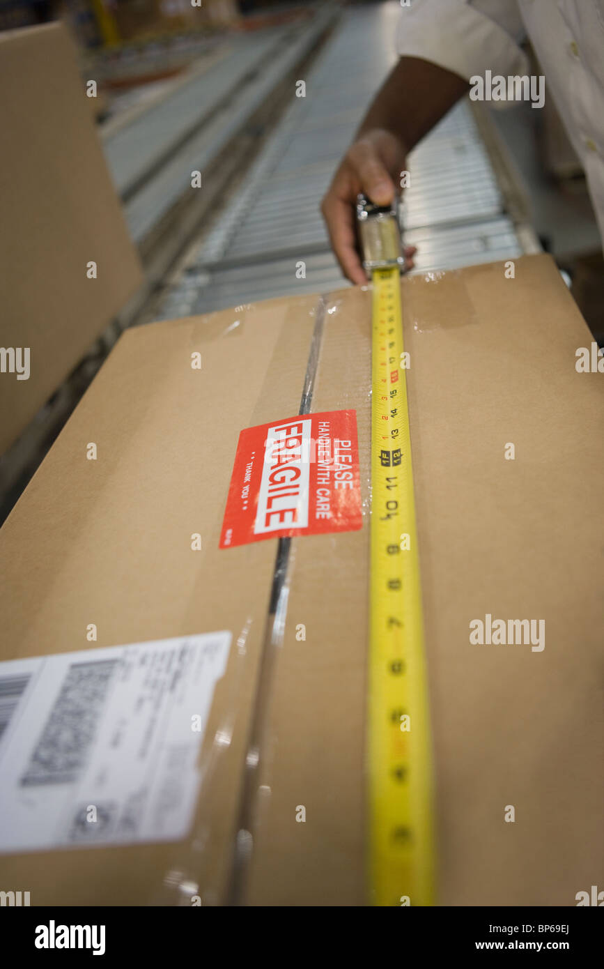 Man measuring cardboard box, close-up Stock Photo