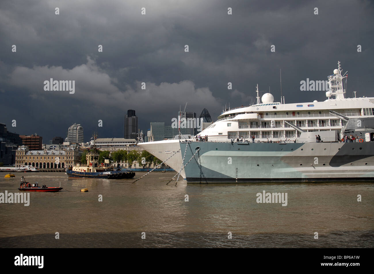 Cruise liner Silver Cloud moored next to HMS Belfast on the River Thames with The Natwest Tower and Gherkin in the background Stock Photo