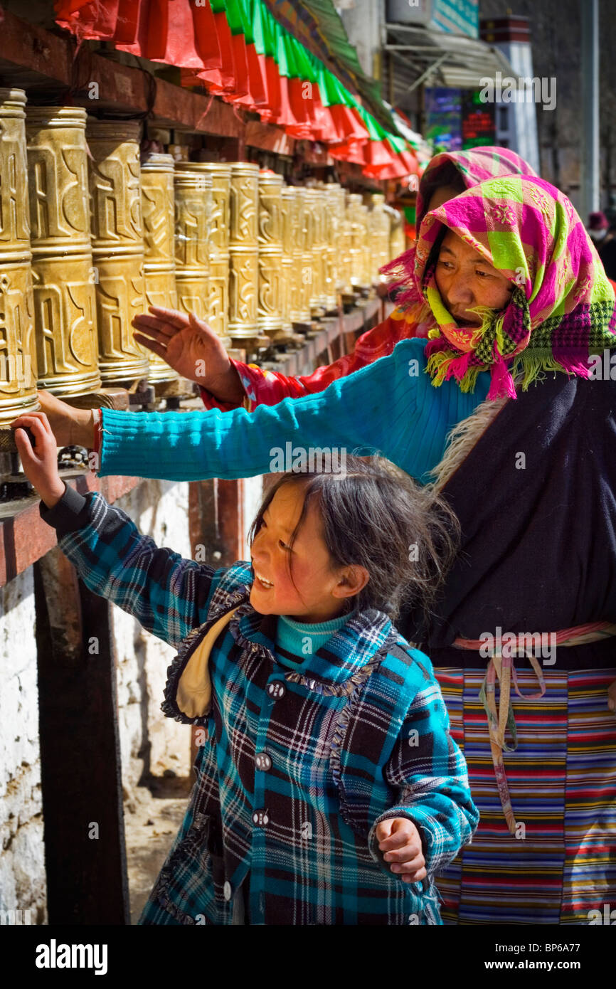 A family walk around the potala palace kora, spinning mani prayer wheels. Stock Photo