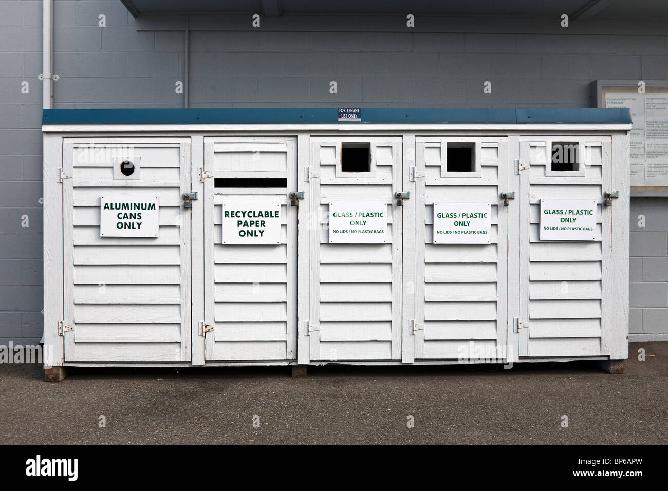 trim neatly labeled white painted wood recycling cabinet with five bins  below a single green formica top at Edmonds marina Edmonds Washington Stock Photo