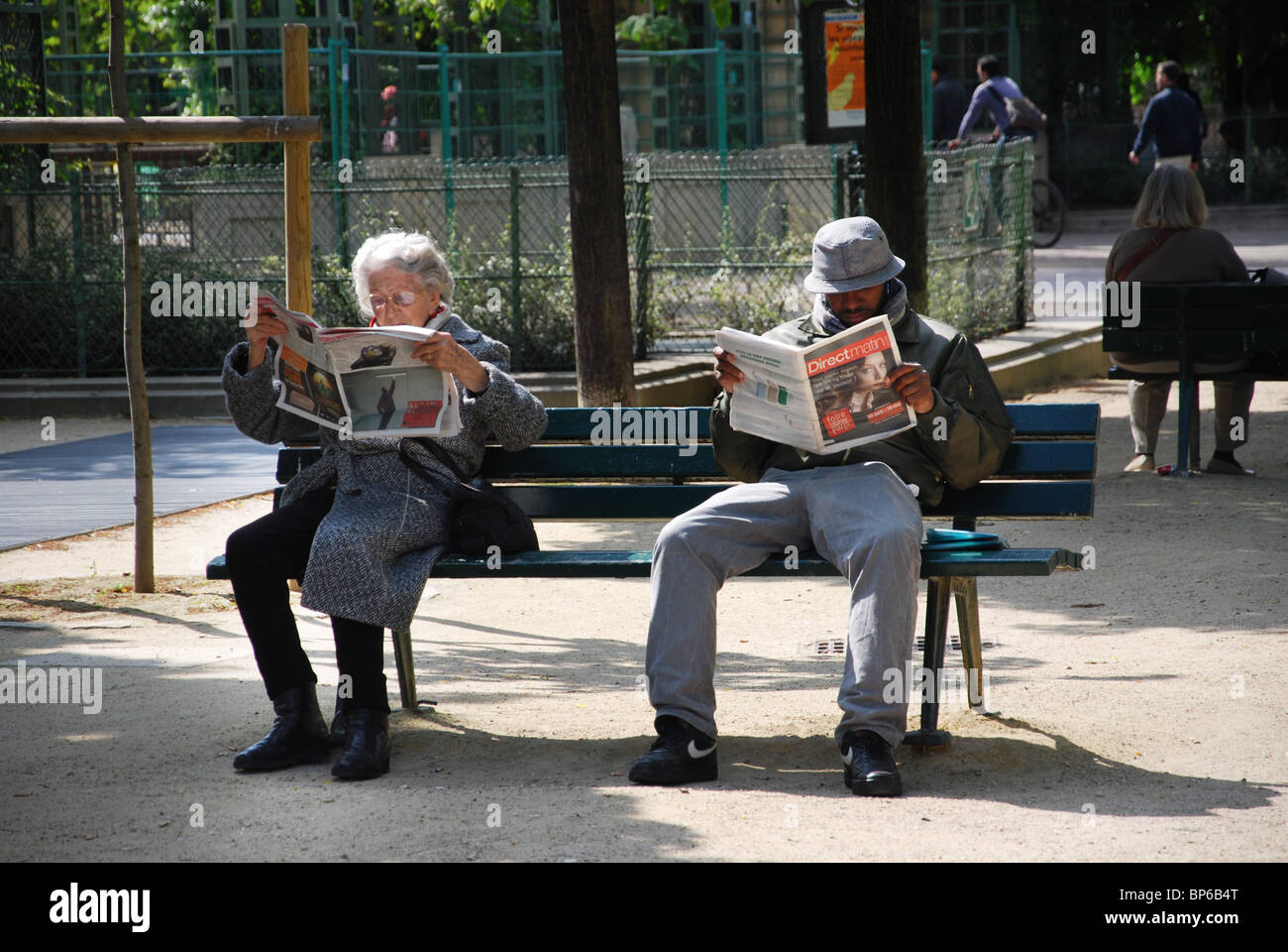 people reading newspaper on Parisian park bench France Stock Photo