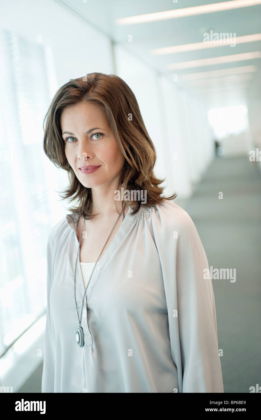 Portrait of a woman standing in a corridor and smiling Stock Photo - Alamy