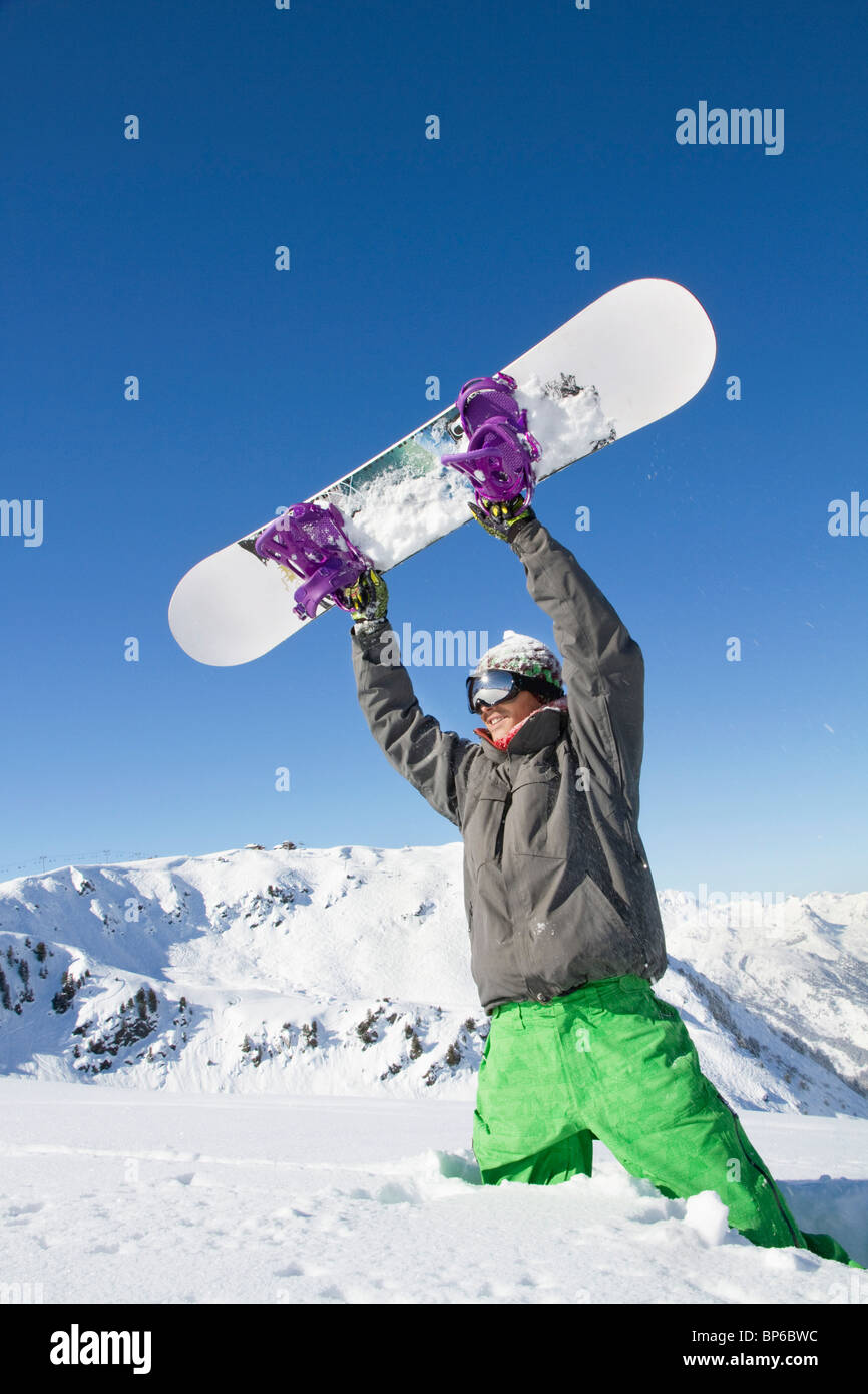 Young man holding his snowboard above his head Stock Photo - Alamy