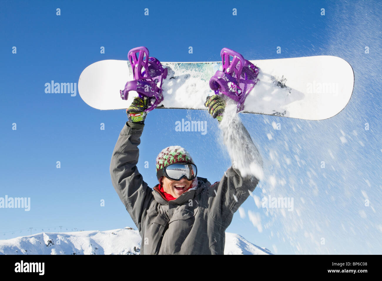 Young man holding his snowboard above his head Stock Photo - Alamy