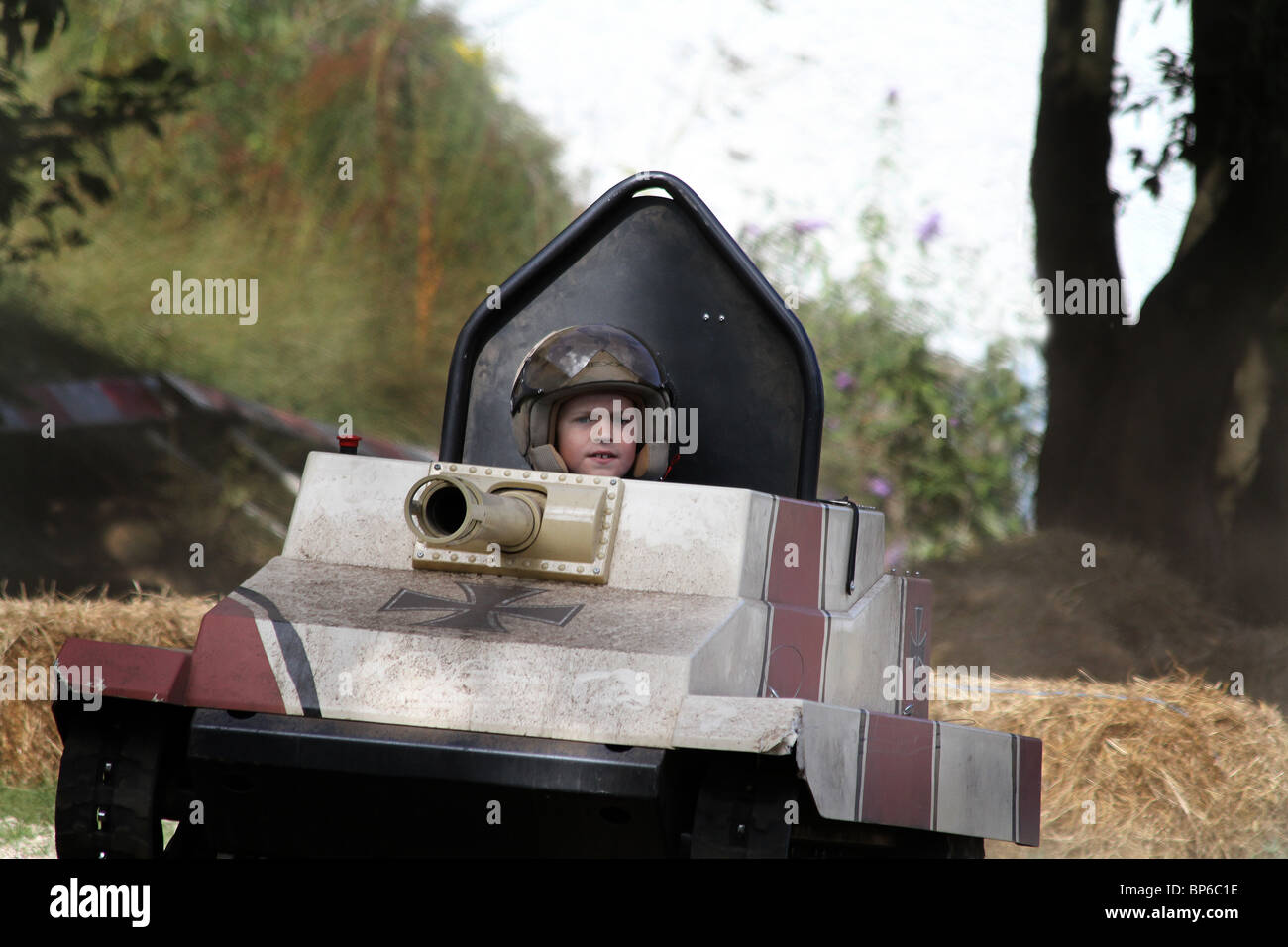 You boy with helmet riding and driving a model tank on an assault ...