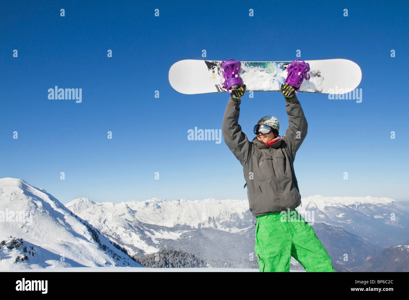 Young man holding his snowboard above his head Stock Photo - Alamy