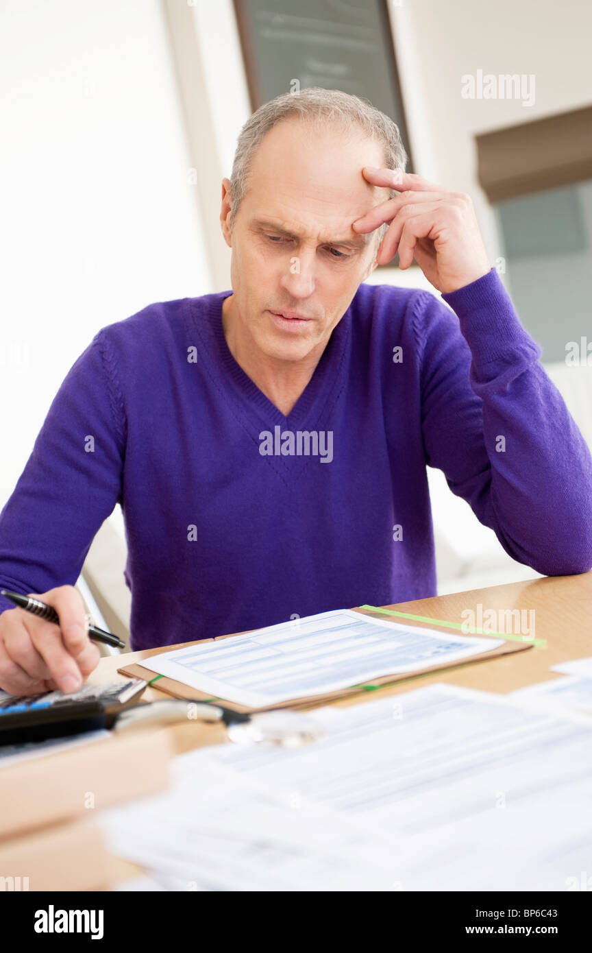 Man using calculator and filling his tax form Stock Photo