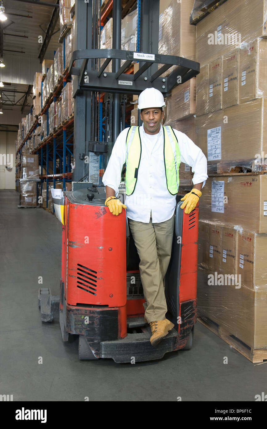 Man standing with fork lift truck in distribution warehouse Stock Photo ...