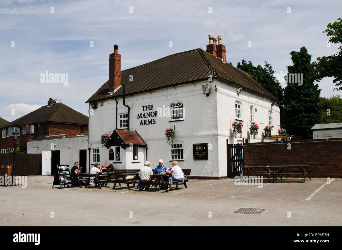 Customers enjoying a drink in the warm sunshine outside The Manor Arms public house, Rushall, Walsall Stock Photo