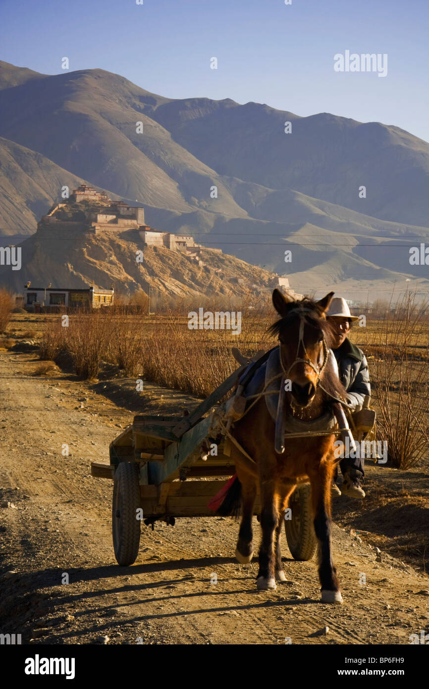 A tibetan man rides his horse away from the Dzong/Fortress of Gyantse in Gyantse, Tibet Stock Photo