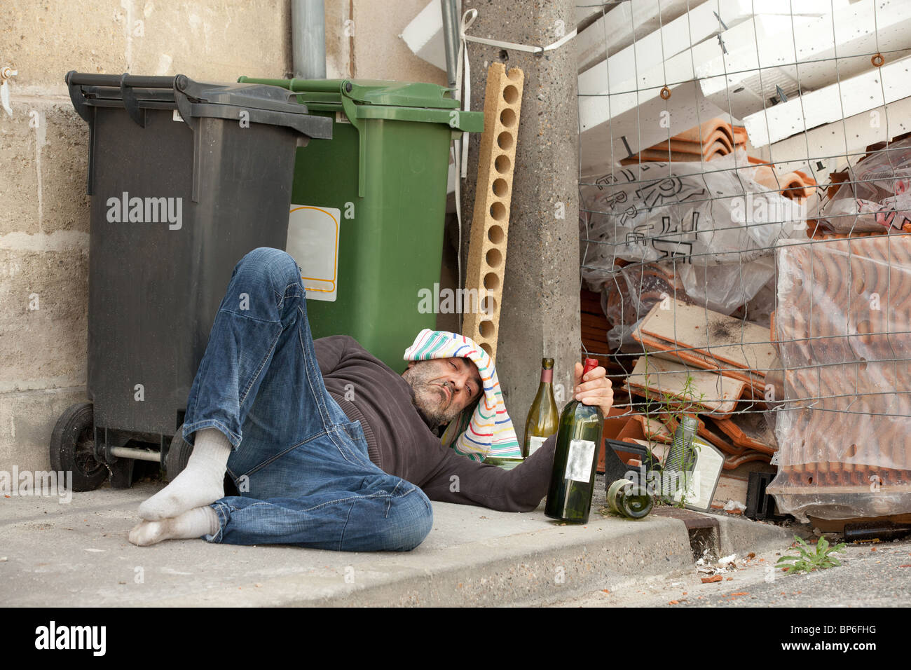 drunk man lying near trashcan in city street Stock Photo