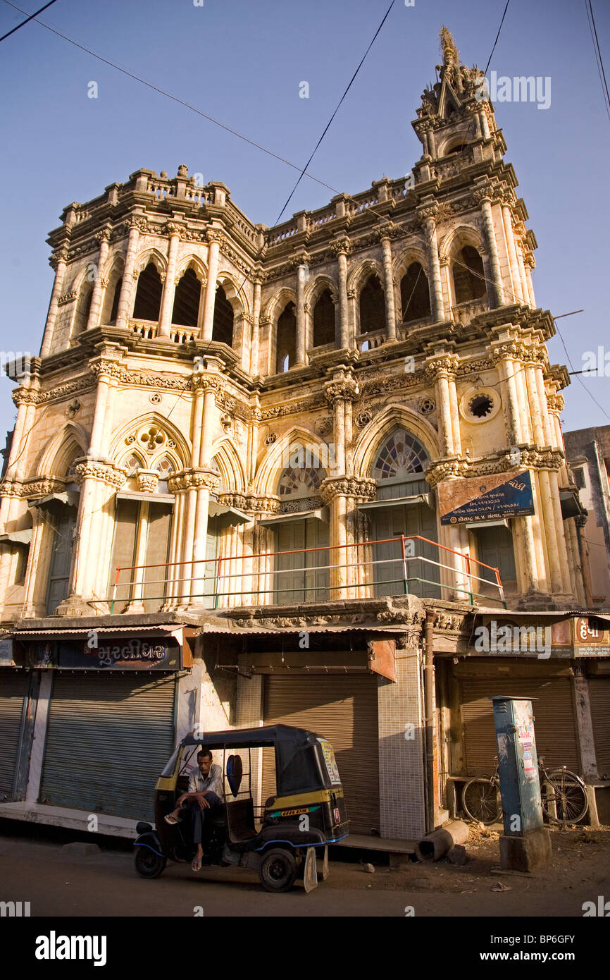 A rickshaw driver sits in front of a once-grand building in Junagadh, Gujarat, India. Stock Photo